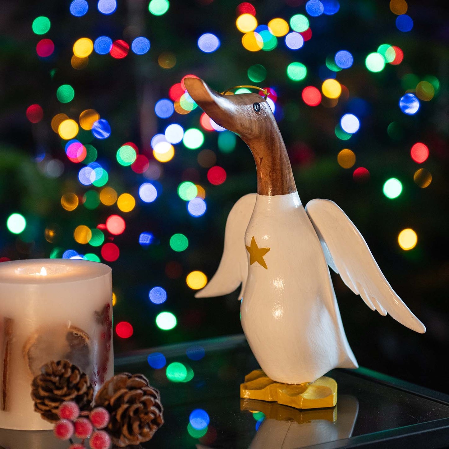 Angel bamboo root duck with white wings and gold star, photographed against Christmas tree bokeh lights