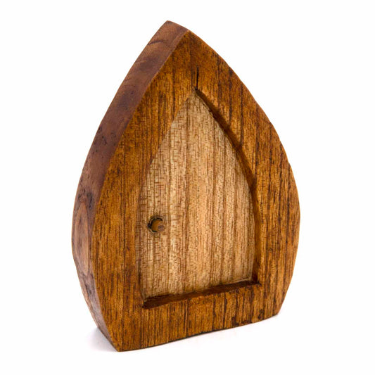 Hand-carved fairy door, three-quarter view showing recessed panel and round knob, amber wood