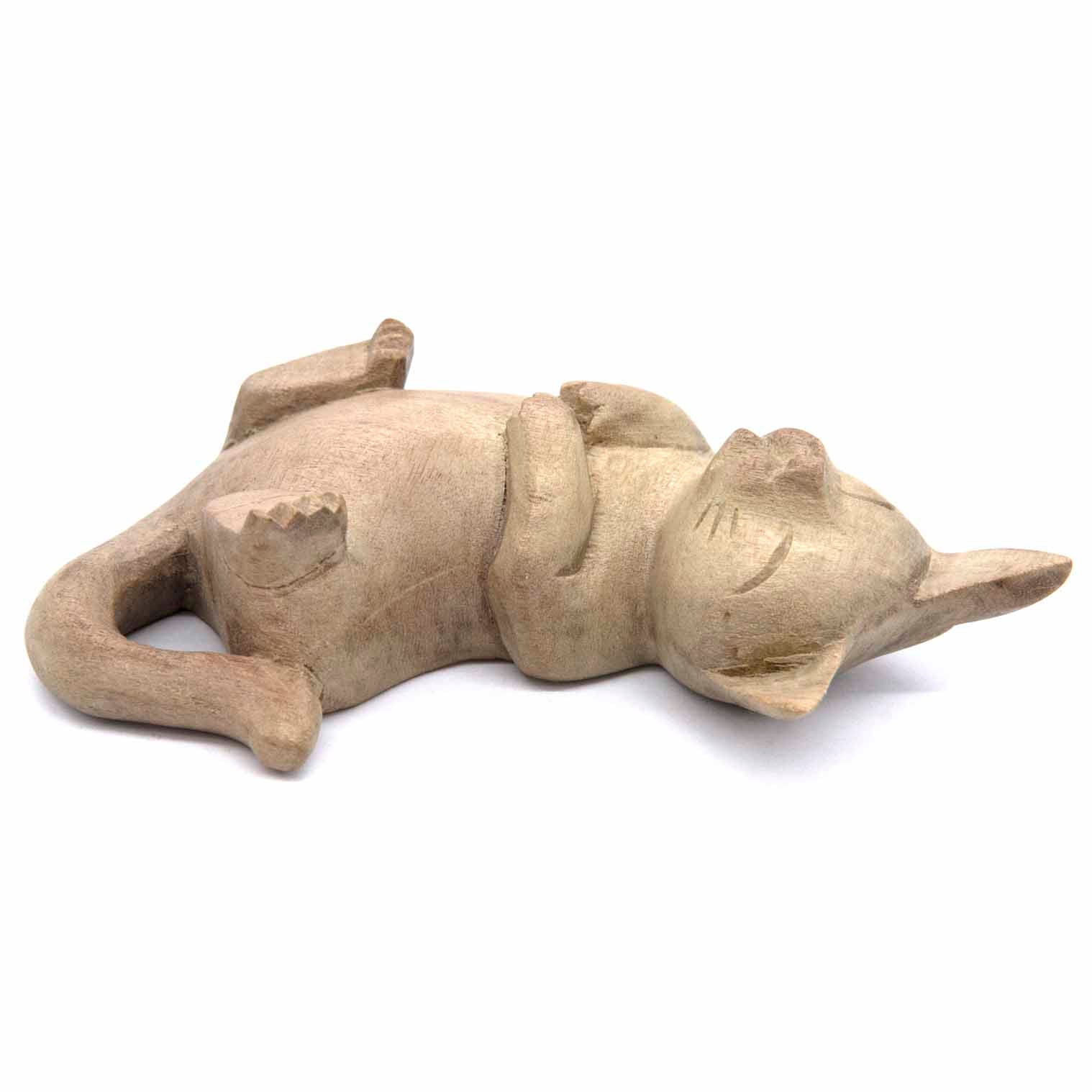 Hand-carved cat figurine lying on its back, legs in the air, bleached wood finish