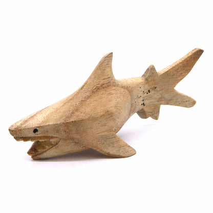 Side view of hand-carved wooden shark with detailed open mouth and fins spread, honey-brown wood grain visible