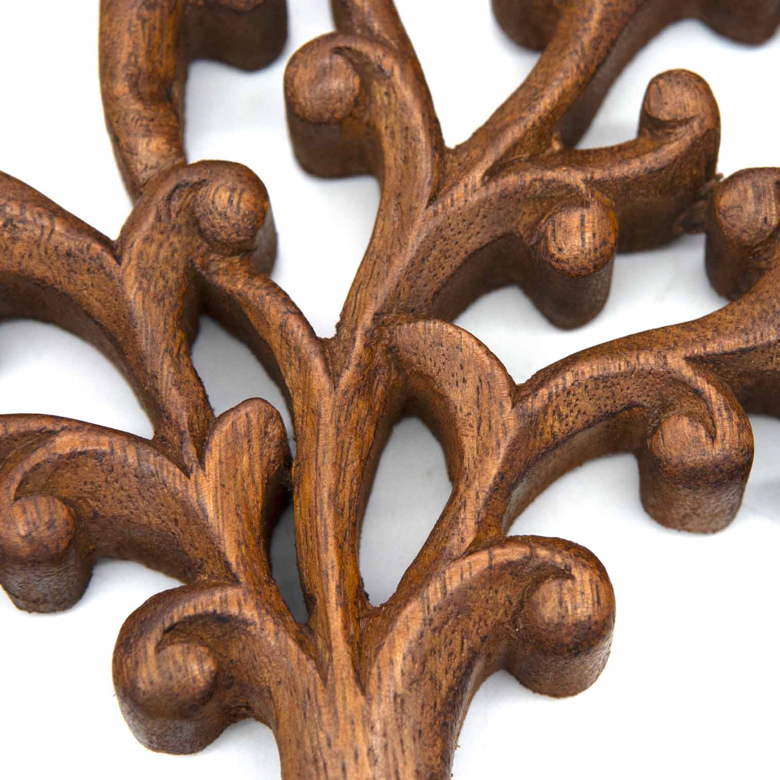 Close-up of carved branch tips on Indonesian Tree of Life plaque showing tight scrolls, buds and warm brown grain