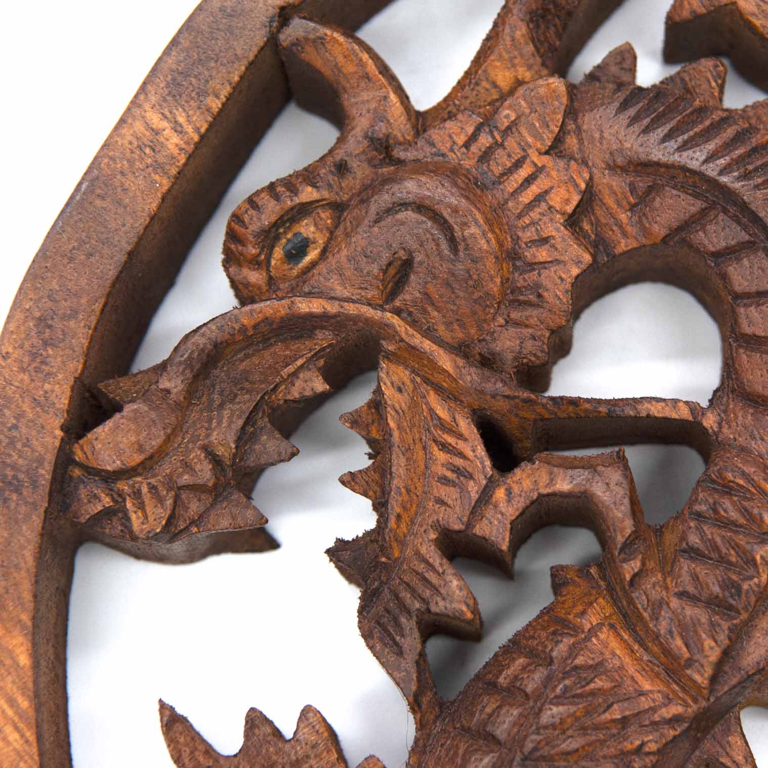 Close-up of dragon head on Indonesian carved wood plaque showing scaled texture, eye detail and open jaw