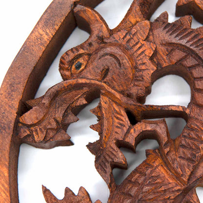 Close-up of dragon head on Indonesian carved wood plaque showing scaled texture, eye detail and open jaw