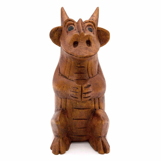 Hand-carved dragon figurine, front view showing expressive face and ridged chest, warm wood