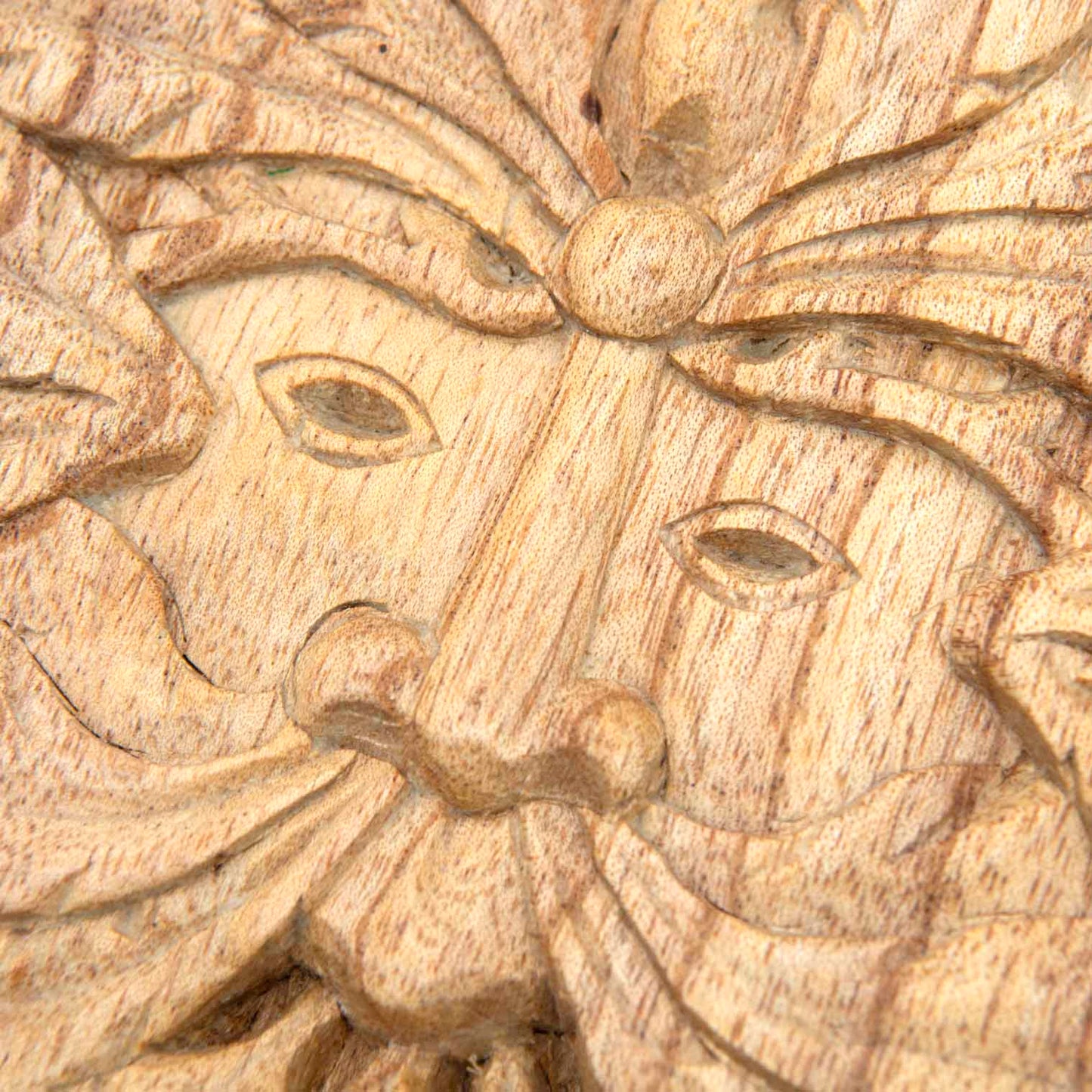 Close-up of Green Man face on Indonesian carved wood plaque showing eyes, nose and leaf beard in pale natural-stained wood