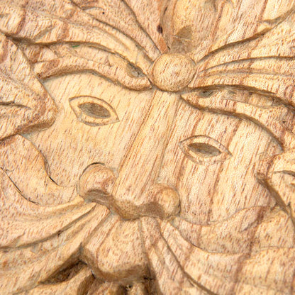 Close-up of Green Man face on Indonesian carved wood plaque showing eyes, nose and leaf beard in pale natural-stained wood