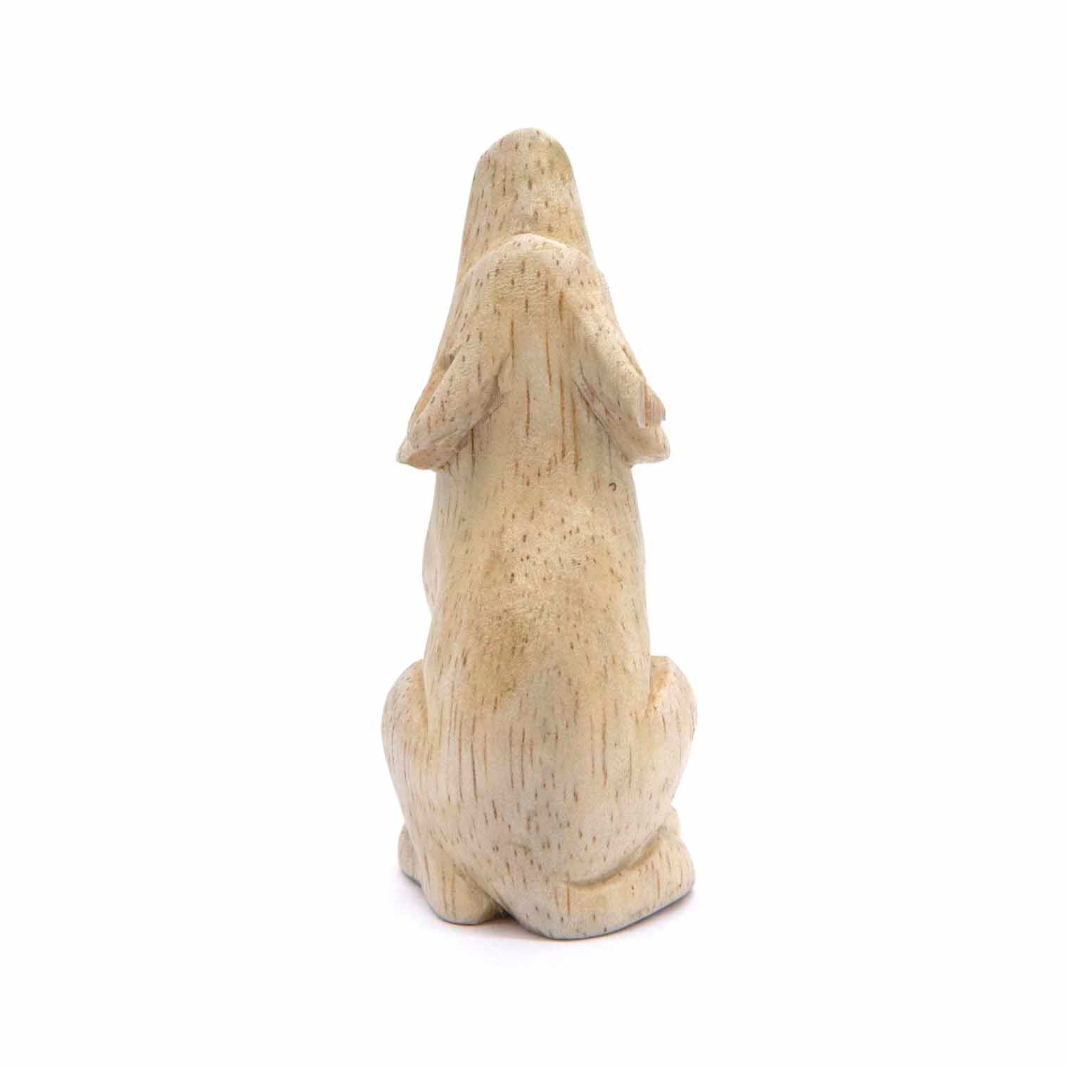 Small Indonesian wood wolf carving, side three-quarter view showing seated form and paws