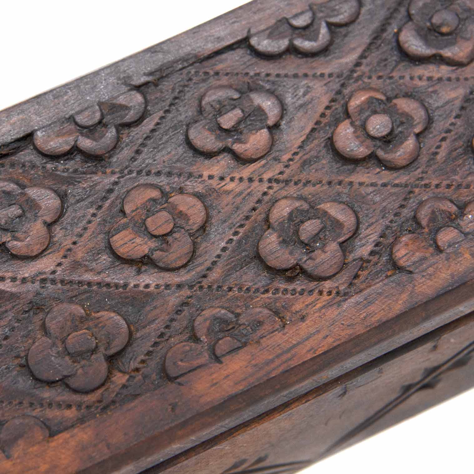 Close-up of raised flower motifs on the lid of the Indonesian carved wood long box, showing chisel detail