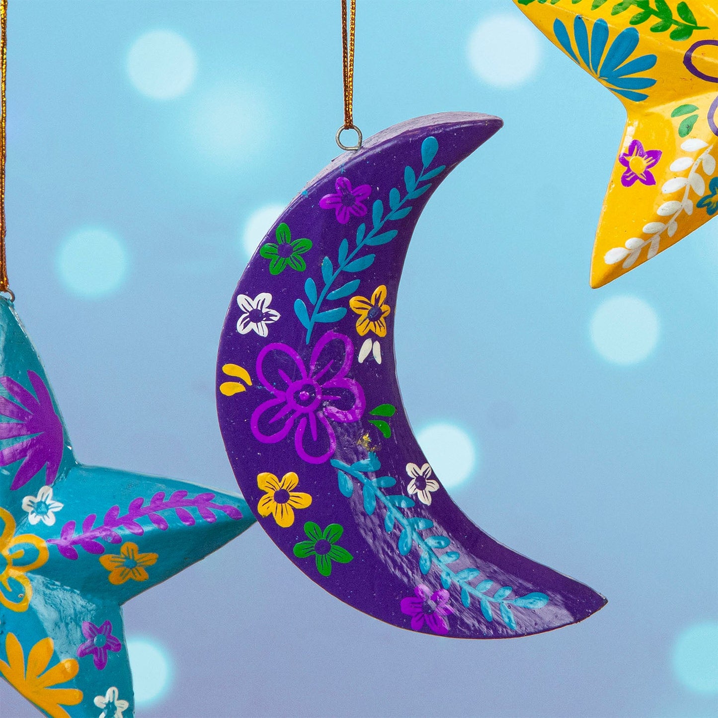 Purple hand-painted wood crescent moon hanging with colourful floral motifs, Bali Indonesia, among other decorations