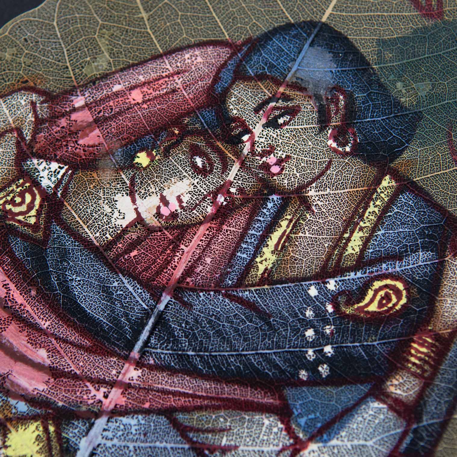 Close-up of peepal leaf painting showing fine brushwork of embracing couple with leaf vein detail, India
