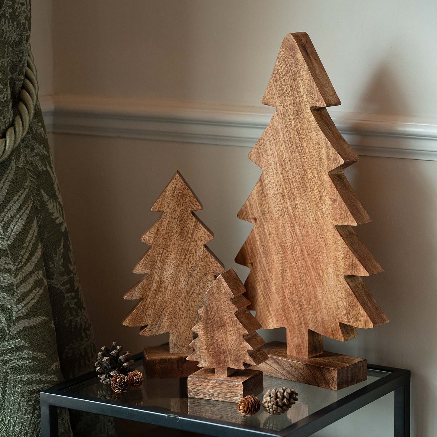 Carved mango wood Christmas tree in small size next to larger carved tree, both with stepped edges and natural wood grain