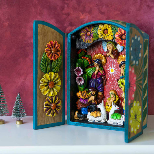 Peruvian nativity retablo open at an angle, showing painted clay figures inside and carved flowers on left door panel