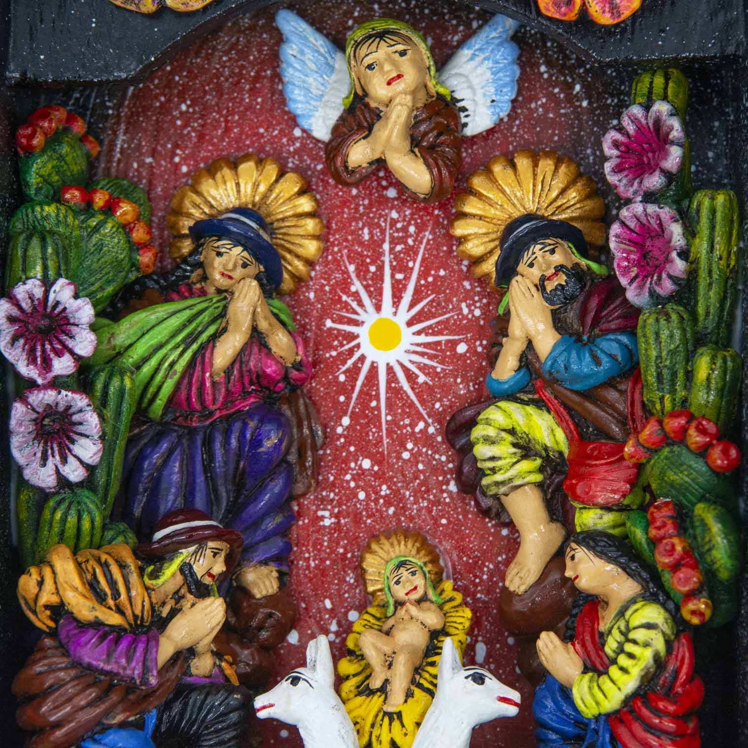 Close-up of nativity scene interior showing hand-modelled clay figures, angel above and llamas below