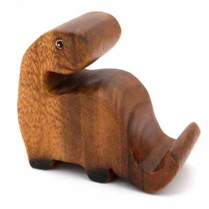 Carved wooden long-necked dinosaur phone stand without phone, three-quarter view showing smooth grain, white background