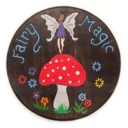 Front view of Fairy Magic painted wood disc on white background, fairy with grey wings standing on red-capped toadstool